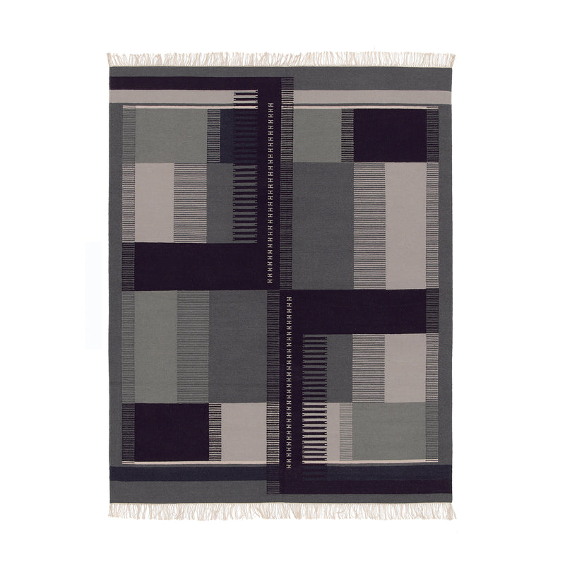 The RH02 Kilim Zet from E15, inspired by Richard Herres designs, features a geometric pattern of rectangles and stripes in gray, black, and beige. Made from hand-spun sheep wool, it is finished with fringed edges on the shorter sides for authenticity.