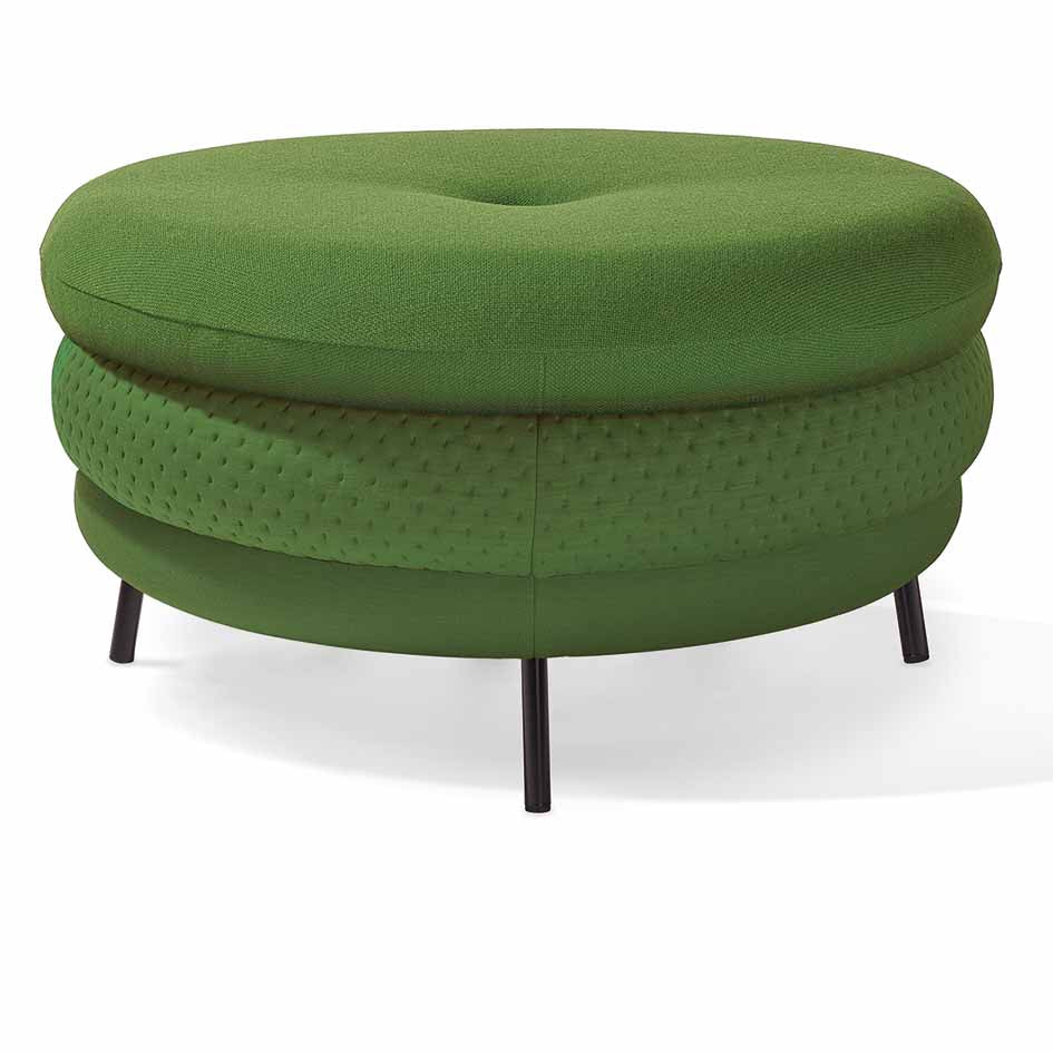 The Fat Tom, a round green ottoman by Richard Lampert, features a tufted top, textured sides, and rests on four sleek black legs. This comfortable piece offers stylish functionality and suits any space perfectly.