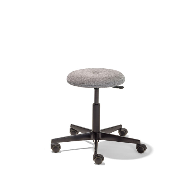 The Richard Lampert Mr. Round Swivel Stool is a space-saving, gray round stool with a fabric-covered seat and black five-wheel base. It features height adjustment via a gas spring system, set against a plain white background.
