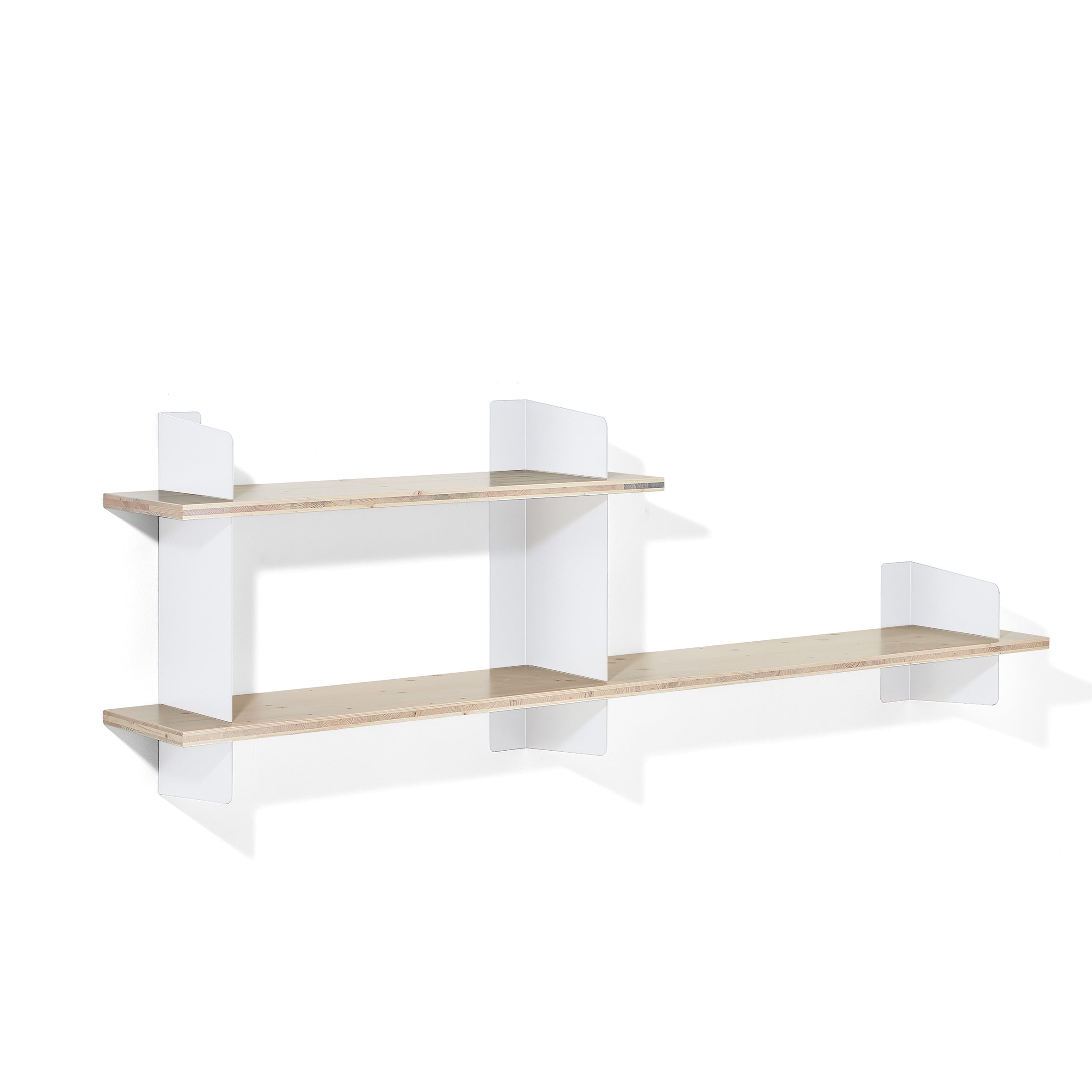 The Atelier by Richard Lampert is a minimalist wall-mounted shelf with two light wooden tiers, and sleek white steel brackets. The shorter upper shelf is elegantly stacked to the left above the longer lower shelf, showcasing modern simplicity against a white background.