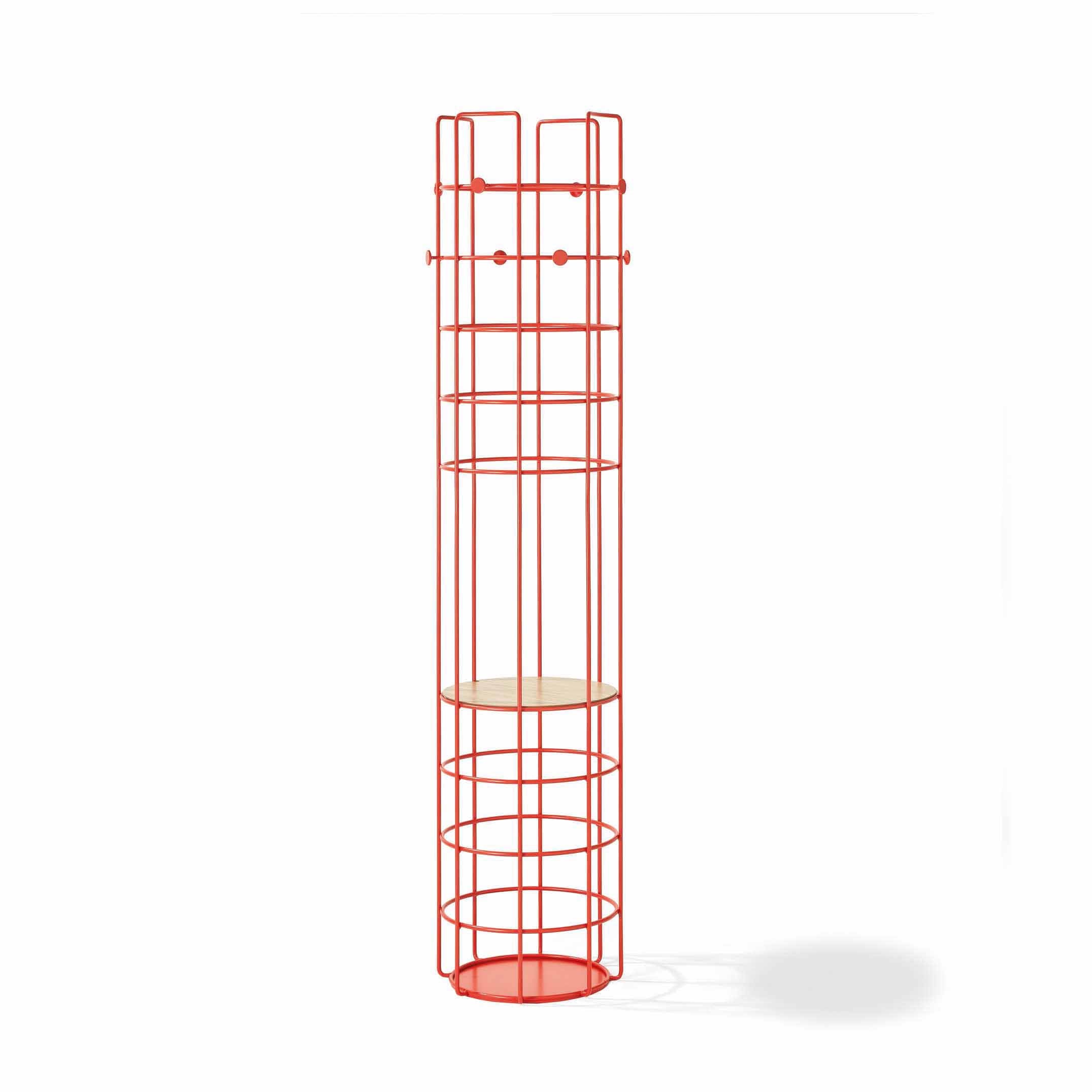 The Bazar Coat Stand by Richard Lampert is a tall, cylindrical metal coat rack with a bold red finish. It features a grid-like structure, multiple top hooks, and a circular wooden shelf in the middle, standing elegantly against a white background.