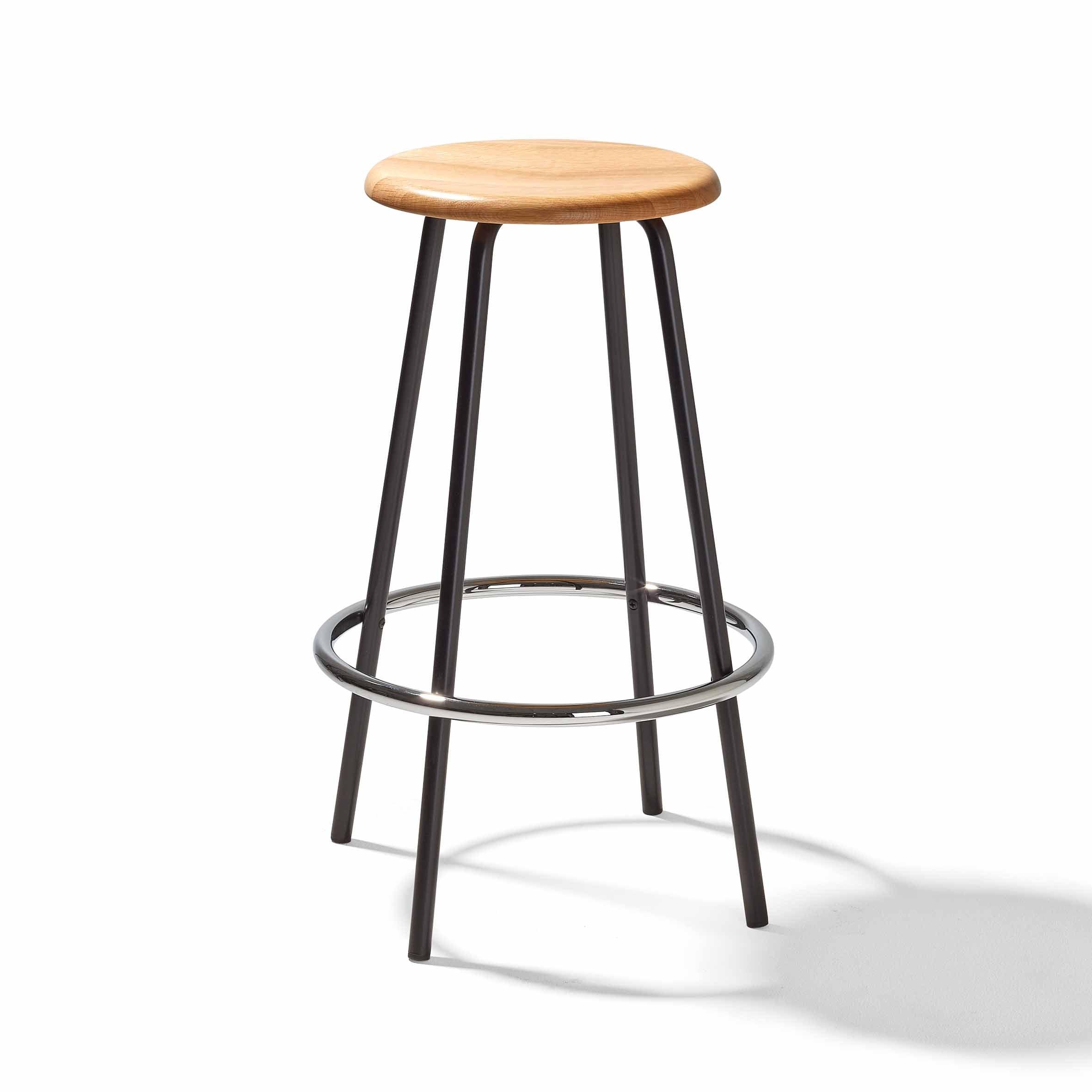 The Richard Lampert Big Tom Barstool has a round wooden seat and black tubular steel legs, with a sleek circular support ring for stability.