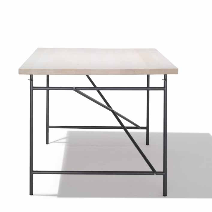 This minimalist Eiermann 1 Table by Richard Lampert features a light wooden top and black metal frame, with geometric sides that cast intriguing shadows on a white surface.