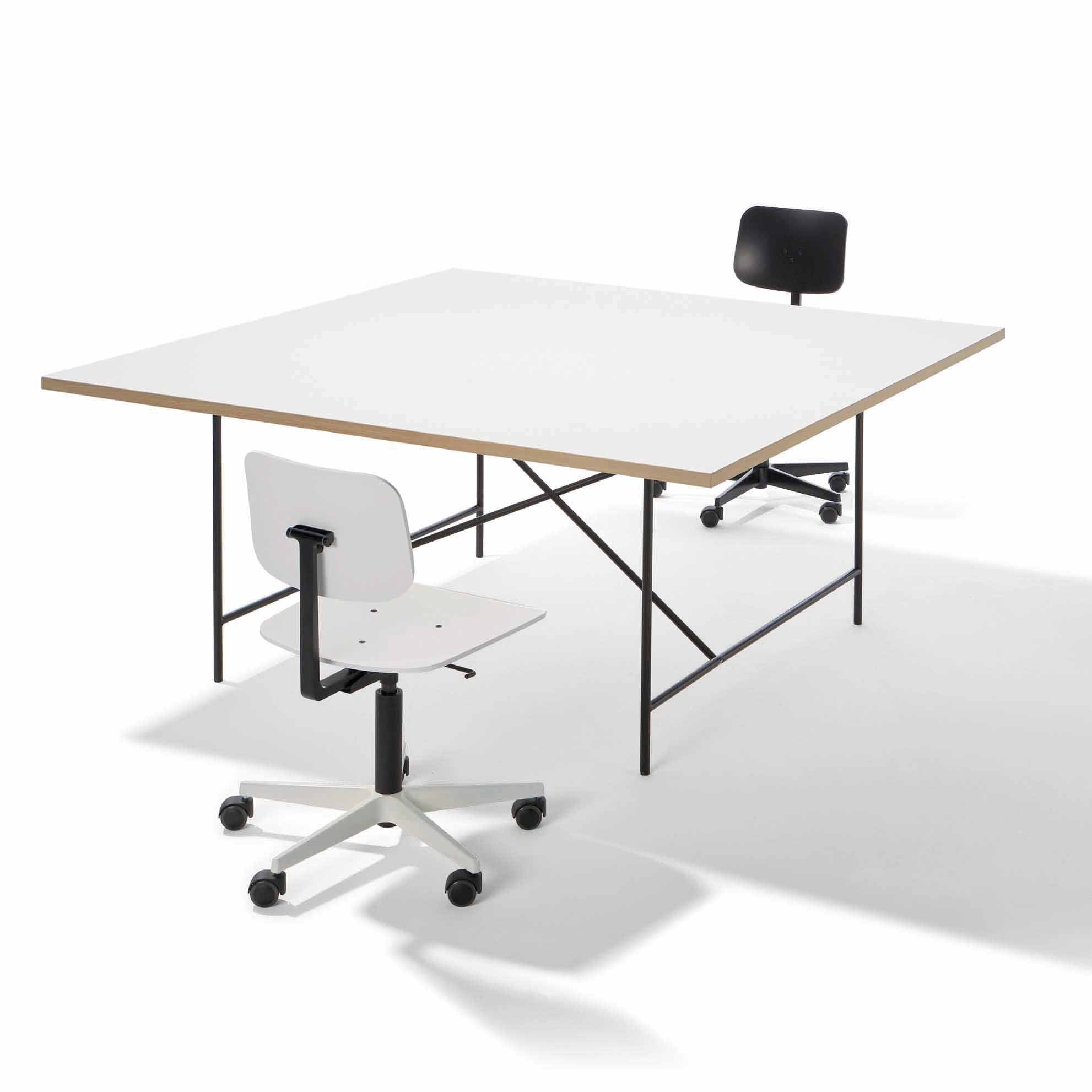 A minimalist setup with a Richard Lampert Eiermann 1 Conference Table featuring a large square white top and black metal legs. Two swivel chairs, one white and one black, are arranged diagonally, highlighting sleek furniture design.