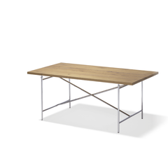 The Eiermann 2 Table by Richard Lampert features a natural wood-finished rectangular top and sleek, crossed stainless steel legs. Its modern minimalist aesthetic is reminiscent of Egon Eiermanns iconic designs.