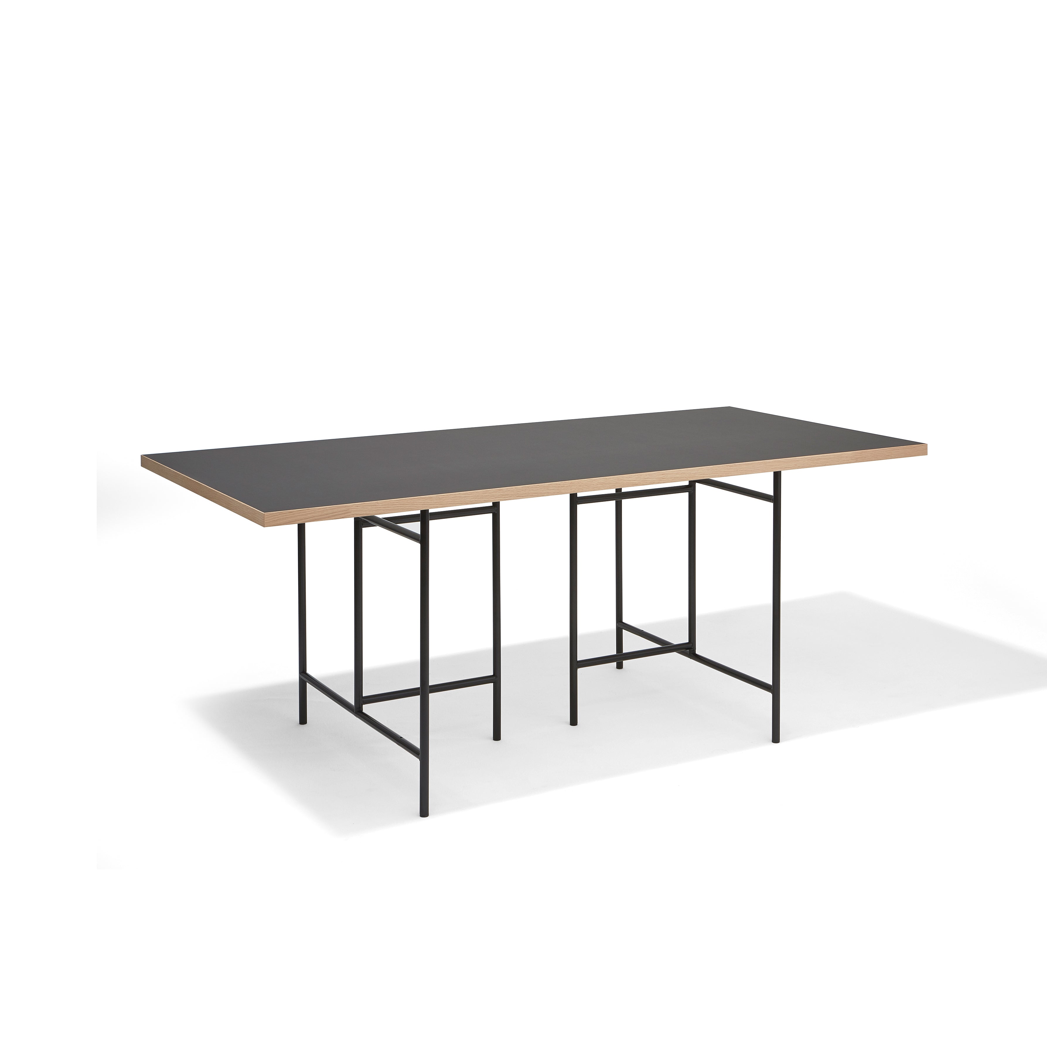 The Eiermann 3 Table by Richard Lampert features a black top with light wood edges and a thin metal frame with geometric legs. Ideal as a worktop or conference table, it stands out against a plain white background with its sleek, minimalist design.