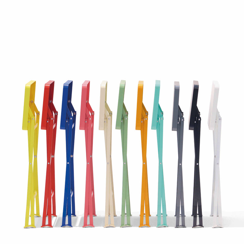 Ten colorful abstract humanoid sculptures in vibrant hues—yellow, red, blue, pink, beige, orange, green, teal, black, and white—stand upright with legs slightly apart against a plain white background. Note: Product featured is unrelated to Flip Side Table by Richard Lampert.