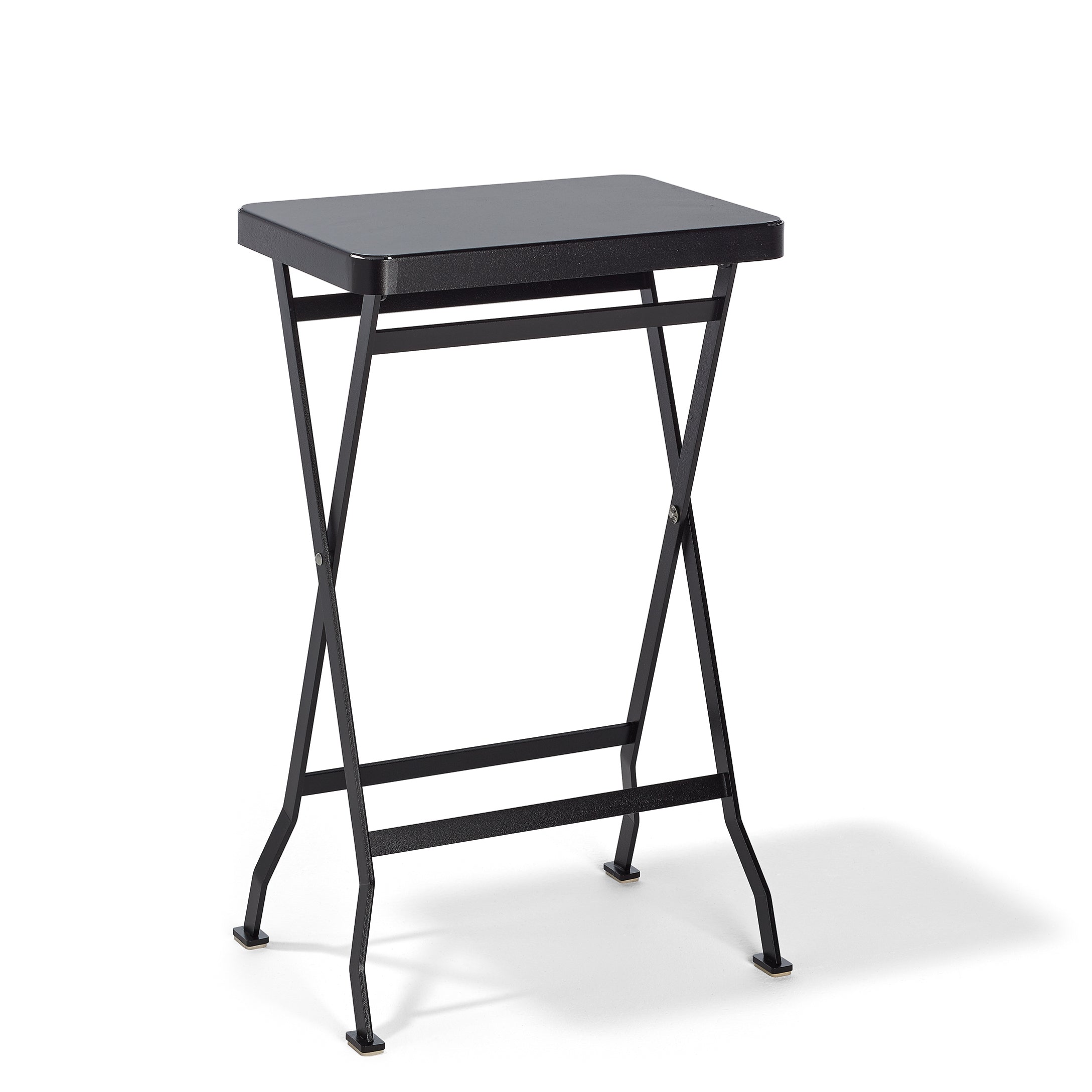 The Flip Side Table by Richard Lampert is a sleek, black folding table featuring a rectangular surface and crossed stainless steel legs, set against a white background.