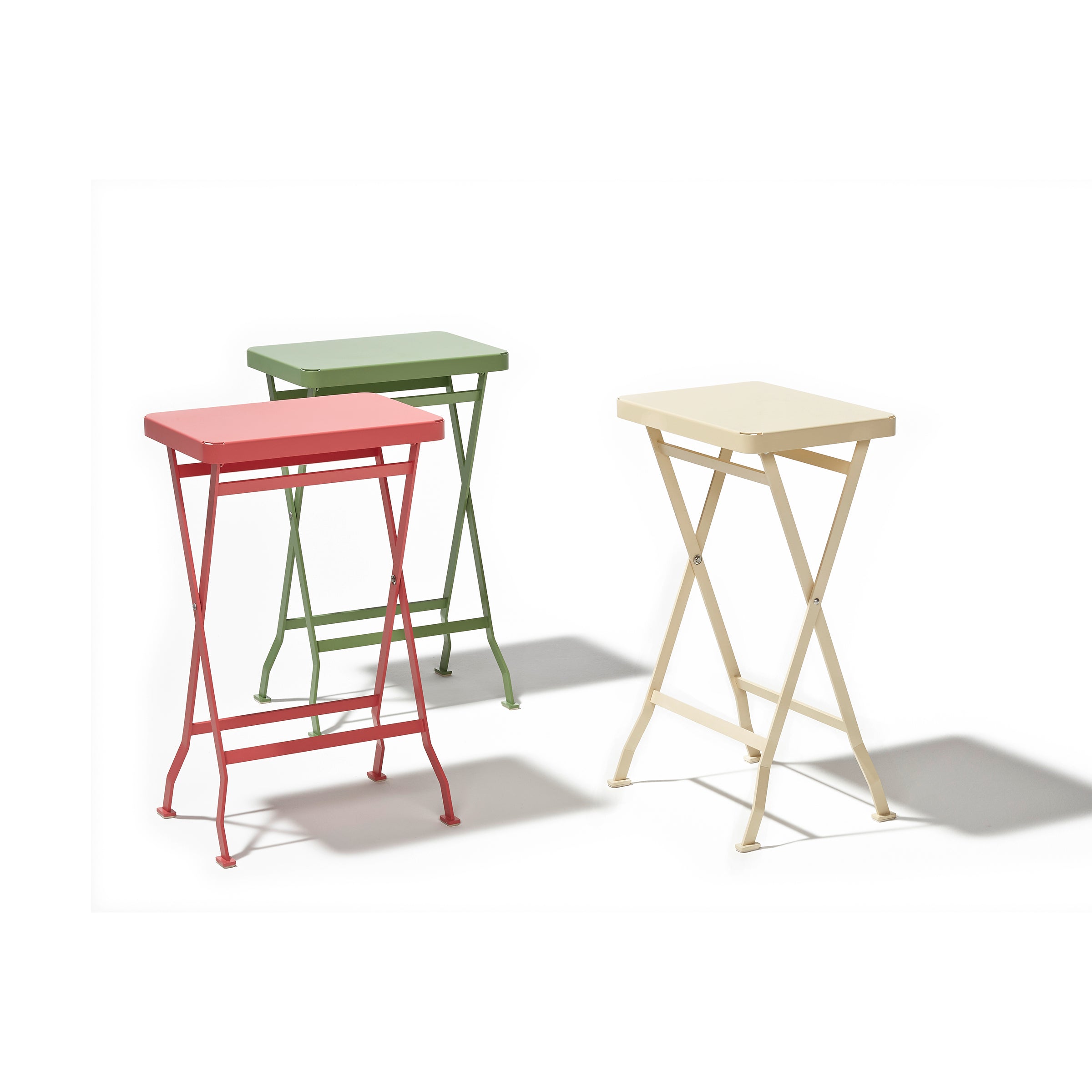 The Richard Lampert Flip Side Tables, in red, green, and cream, feature rectangular tops on slender cross-legged stainless steel frames. Set on a white background, they highlight minimalist design and premium quality.