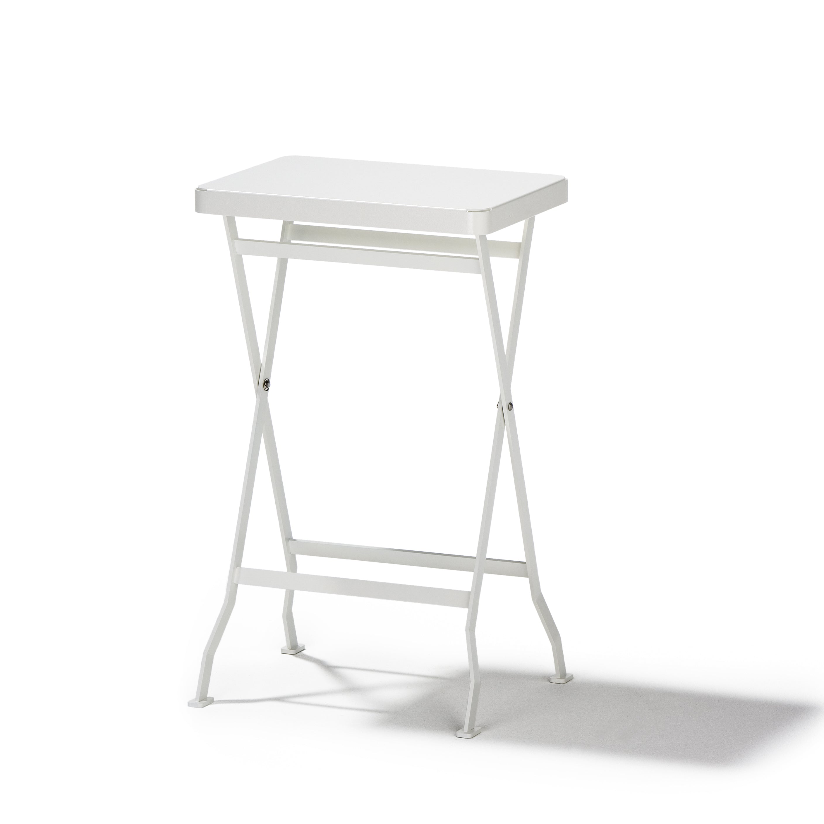 The Flip Side Table by Richard Lampert is a compact white rectangular folding table featuring a premium quality metal frame and crossed legs, set against a white background.