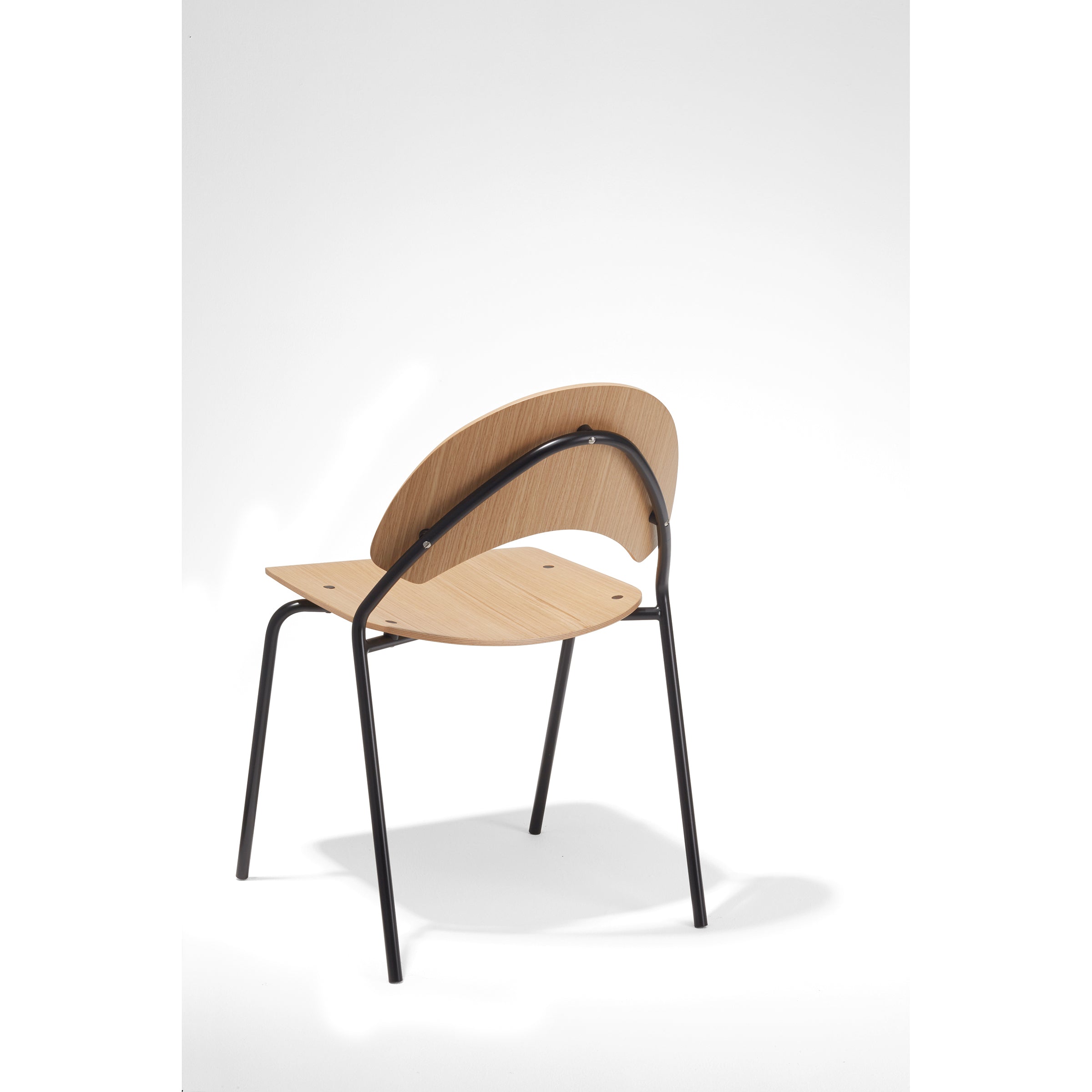 The Frog Chair by Richard Lampert, designed by Herbert Hirche, features a light wood seat and backrest with a black metal frame. It showcases a minimalist design with rounded features and four slender legs against a white background.