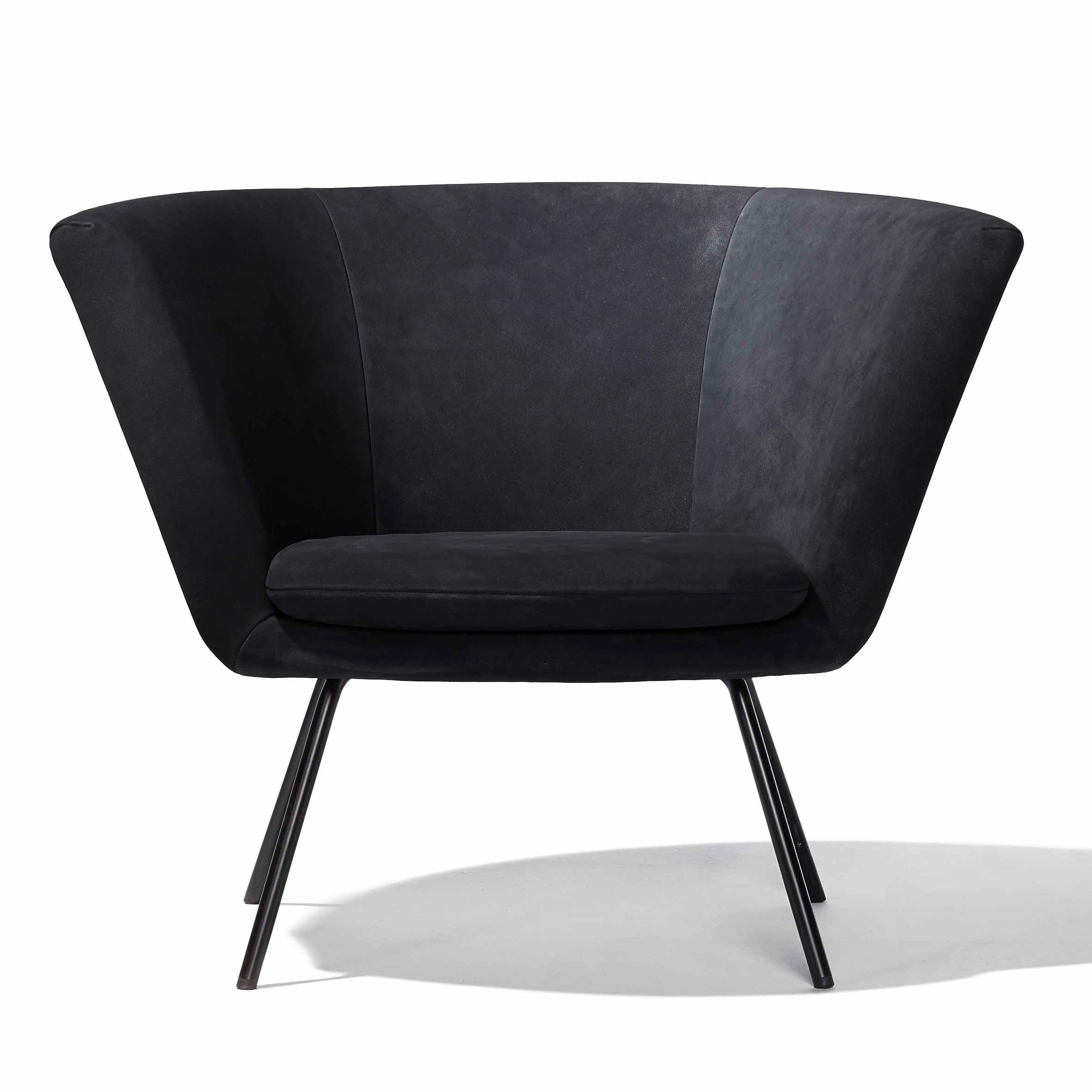 The H 57 Lounge Chair by Richard Lampert is a modern black armchair with a wide, flared backrest and sleek stainless steel legs. Its soft, cushioned seat ensures comfort while reflecting a contemporary and minimalist aesthetic reminiscent of mid-century design.