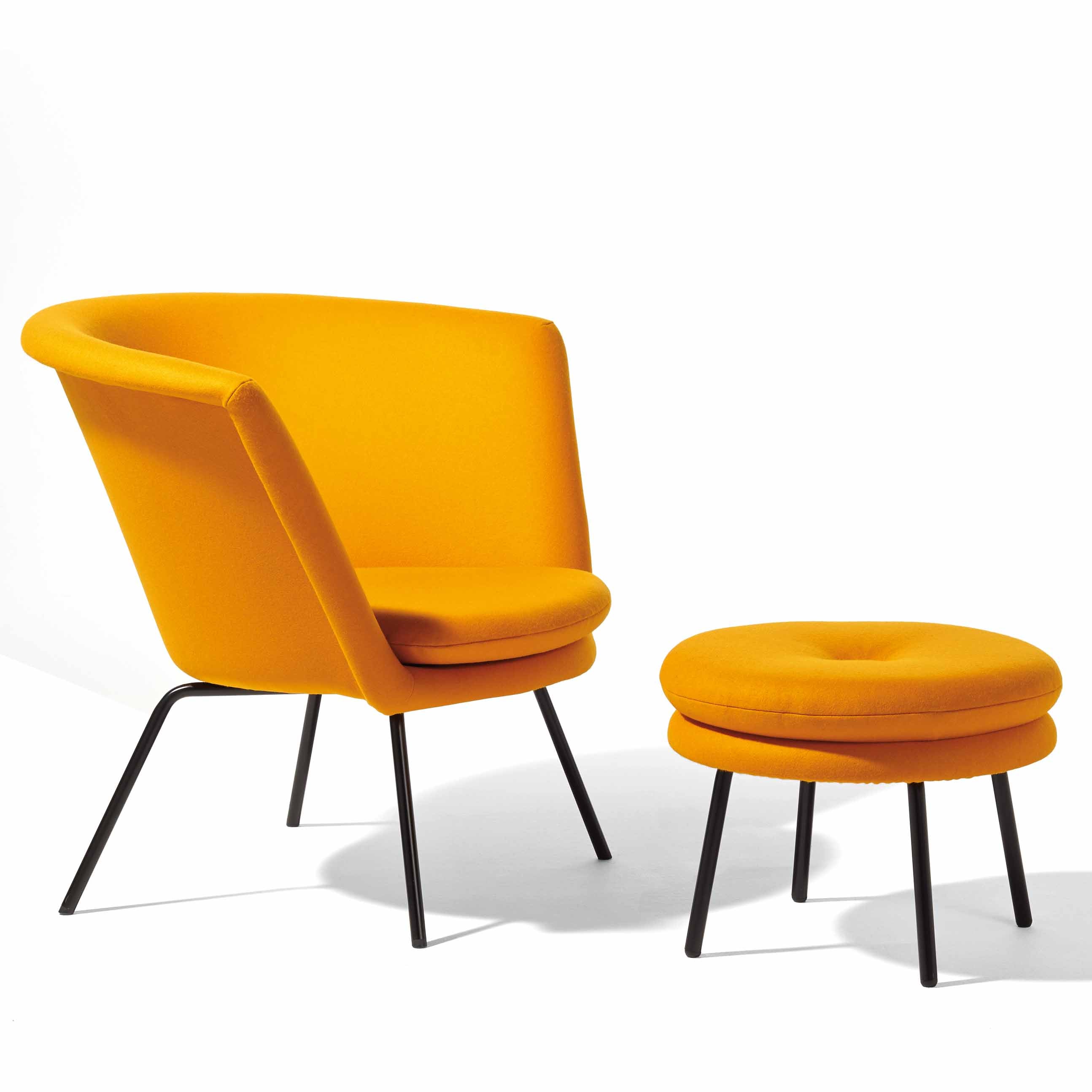 The H 57 Lounge Chair by Richard Lampert, paired with a matching round ottoman, exhibits mid-century design with sleek black metal legs. The chair features a curved backrest and the ottoman a tufted top, echoing Herbert Hirches style. They are displayed against a plain white background.