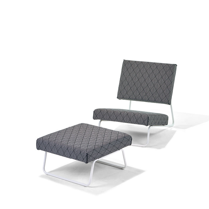 The Richard Lampert Hirche Lounge Ottoman, inspired by Herbert Hirche, showcases a geometric-patterned design. The lounge chair and matching ottoman feature black and white fabric on elegant white metal frames, offering a striking silhouette against a plain white background.