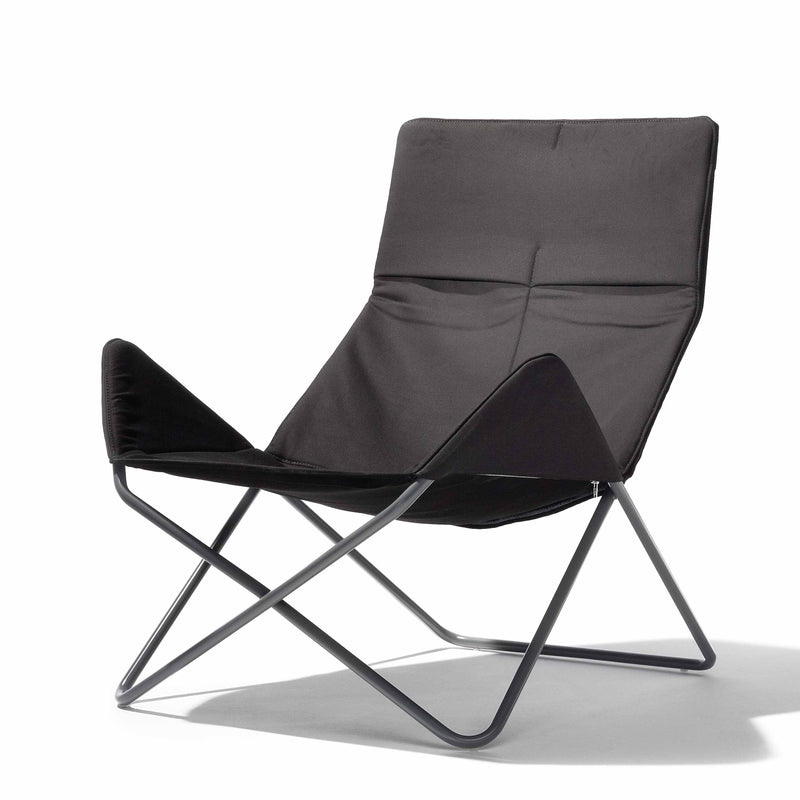The In-Out Chair by Richard Lampert is a modern black lounge perfect for outdoor use. It features a sleek, angular design with a weather-resistant single fabric seat supported by a minimalist metal frame, forming a triangular shape and low-slung armrests.