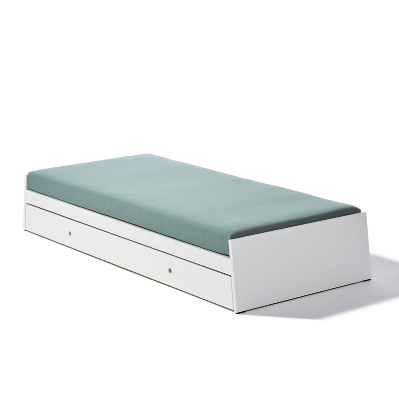 The Lönneberga Stacking Bed by Richard Lampert is a sleek, minimalist white daybed with a teal mattress. Featuring clean lines and a pull-out drawer for storage, this versatile piece is perfect for saving space in any room.