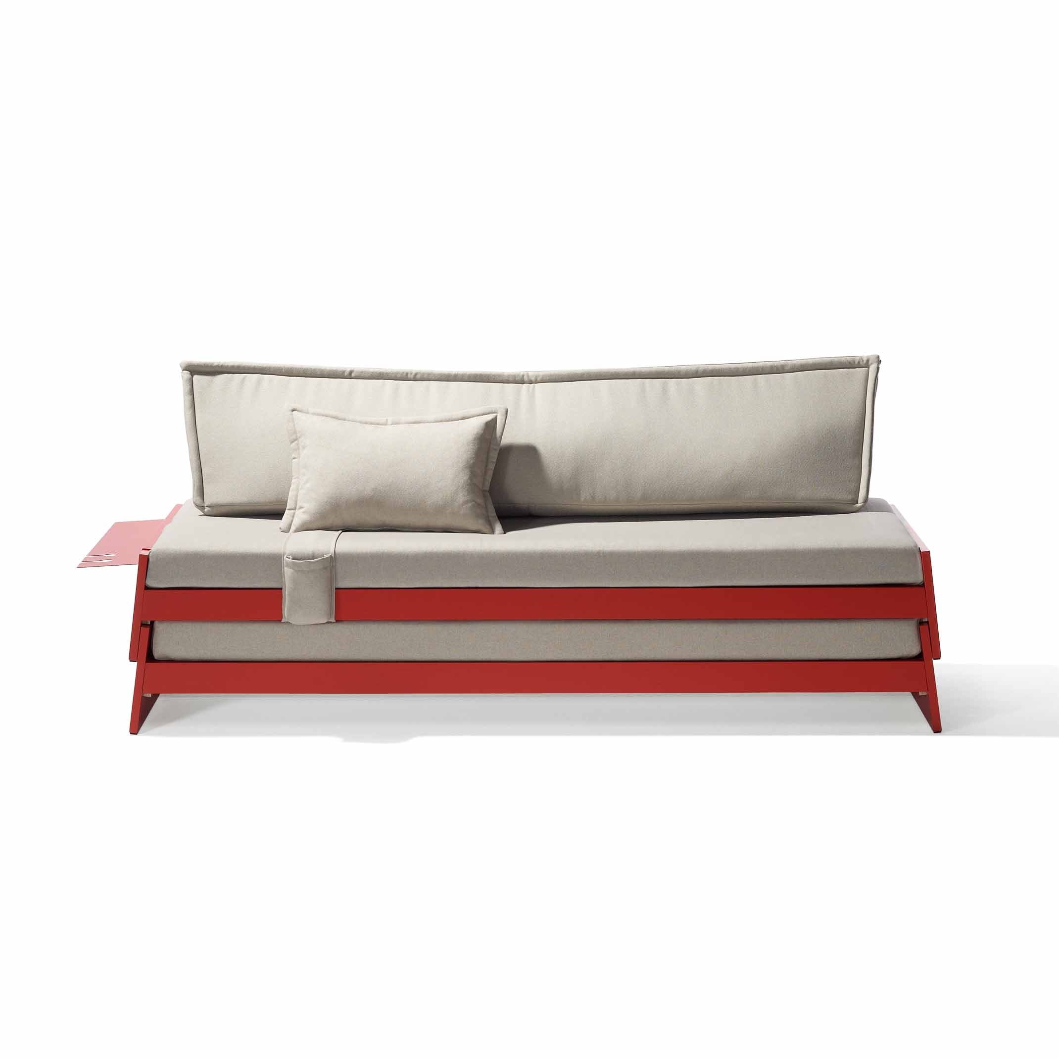 The Lönneberga Stacking Bed by Richard Lampert is a modern, versatile sofa bed featuring a minimalist beige cushion and backrest with a red frame. It includes a matching beige pillow and a space-saving red side table attached to the left side.
