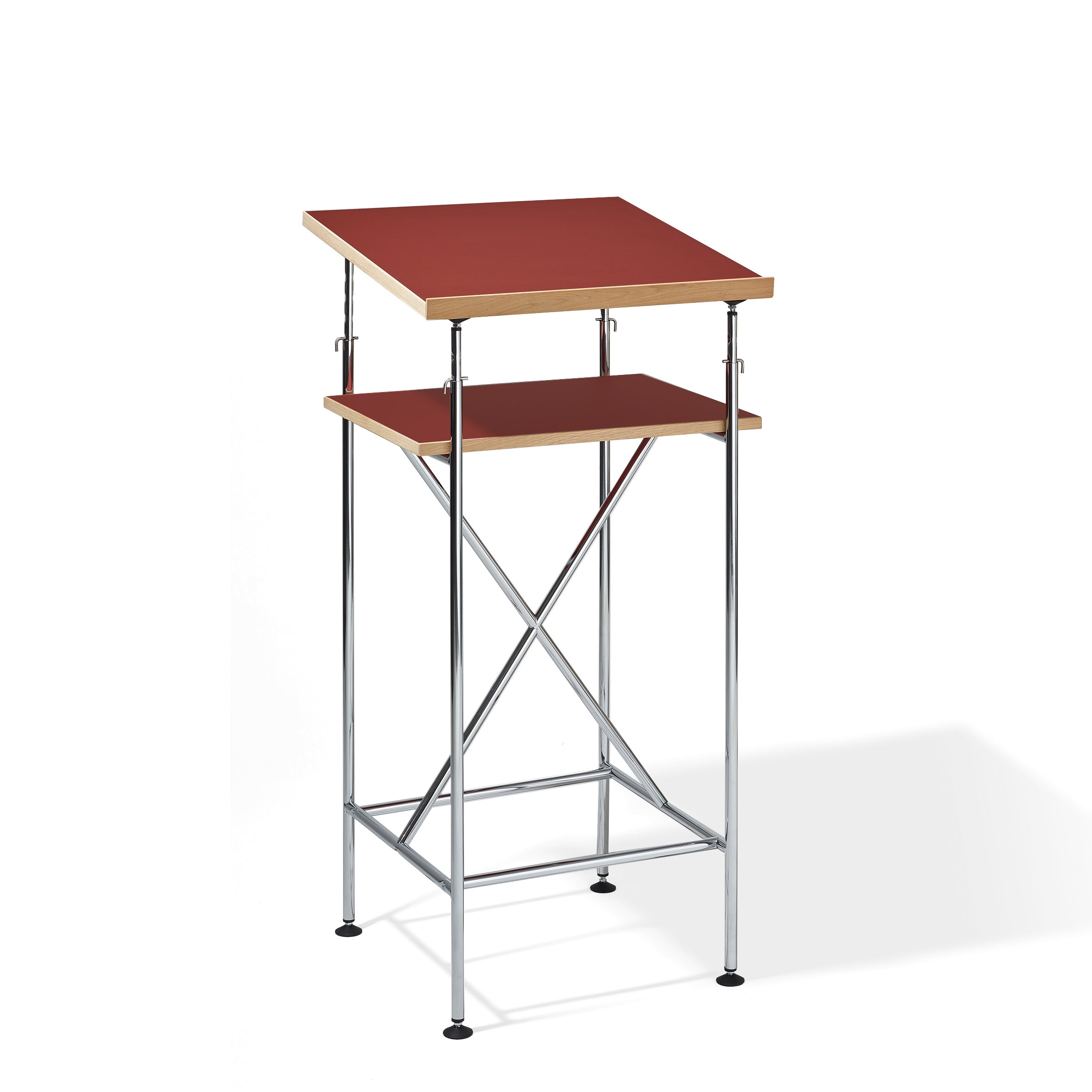 The Milla High Desk by Richard Lampert features a sleek, minimalist design inspired by the Eiermann table, with a red tabletop, wooden lower shelf, and sturdy chrome metal frame with crossbars for active sitting or standing.