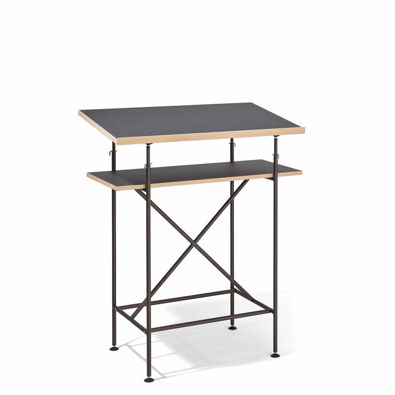 The Milla High Desk by Richard Lampert features a sleek black top and a secondary shelf, all supported by a black metal frame with X-shaped crossbars for stability. Inspired by the Eiermann table, its perfect for active sitting or standing in a minimalist style.
