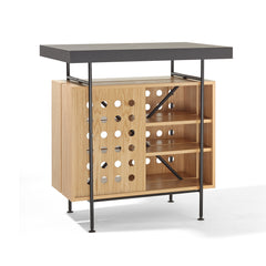 The Milla Bistro Table by Richard Lampert showcases a dark tabletop with black metal legs. The left side features a perforated design, and the right has open shelves for storage, giving it a sleek, contemporary appeal suitable as a chic bar table.