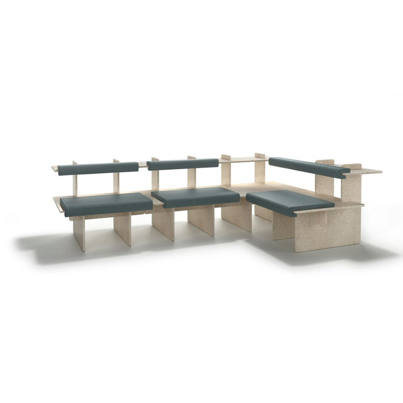 The Pip by Richard Lampert is a customizable modular seating arrangement featuring light wood panels and dark green upholstered cushions in an L-shape. Its minimalist design suits contemporary living spaces or public areas, set against a white background.