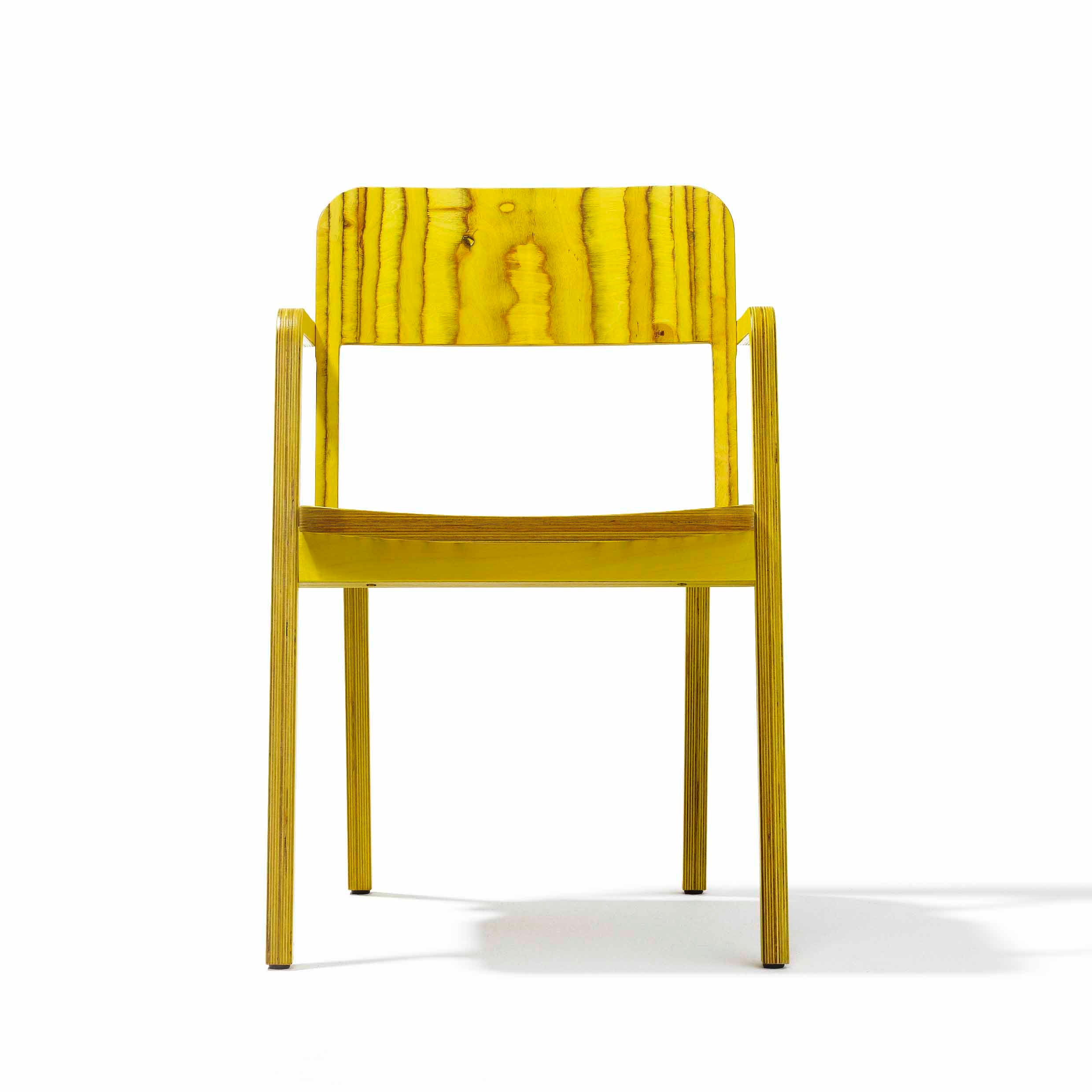 The Prater Chair by Richard Lampert is a modern wooden chair made of birch plywood, featuring a vibrant yellow backrest and seat with natural wood grain patterns. It has sleek lines reminiscent of Viennese wooden chairs and is photographed against a plain white background.