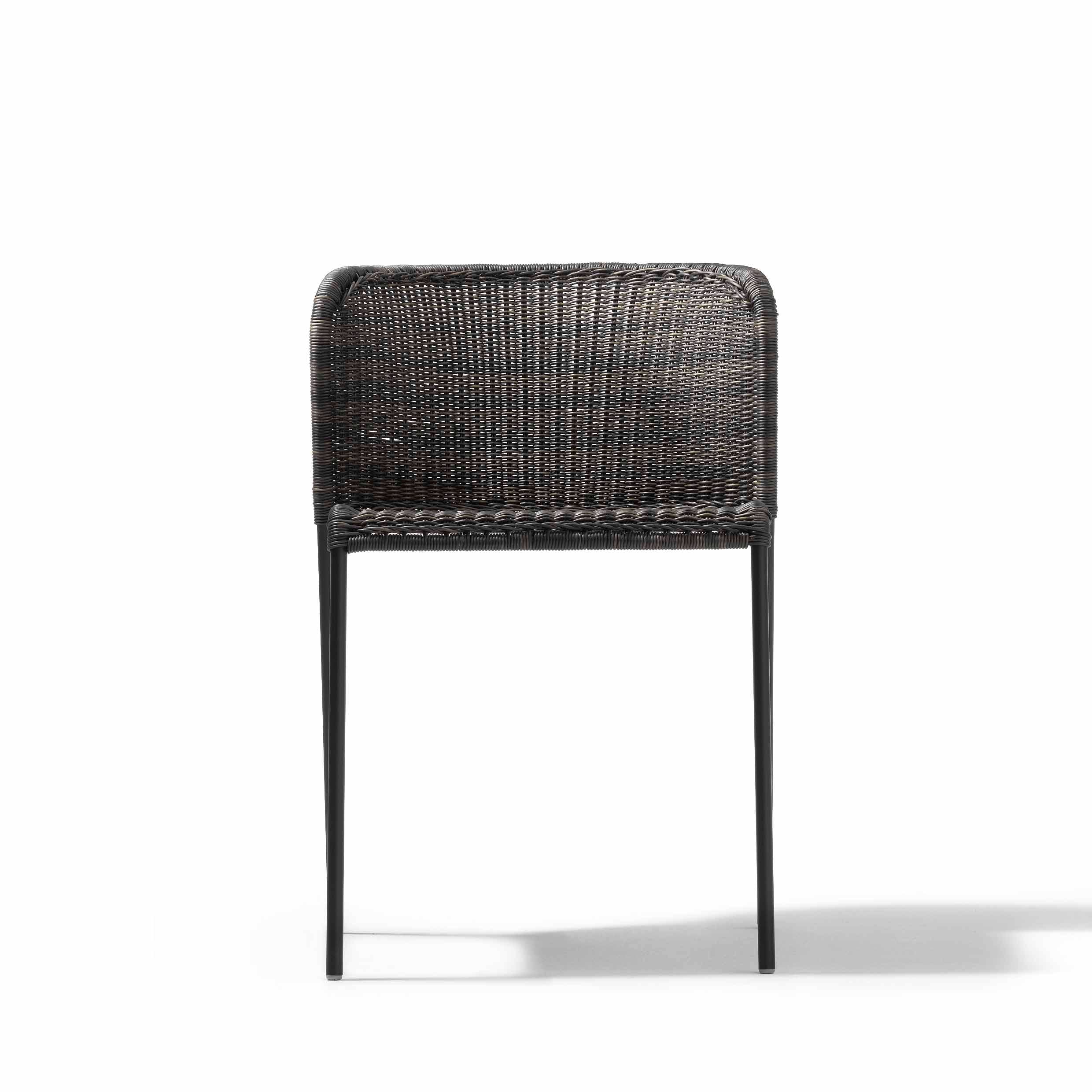The Santa Lucia chair by Richard Lampert features a front view with a woven, dark-brown wicker backrest and seat, sleek straight black metal legs evoking tubular steel designs, and is highlighted against a plain white background enhancing its modern aesthetic.