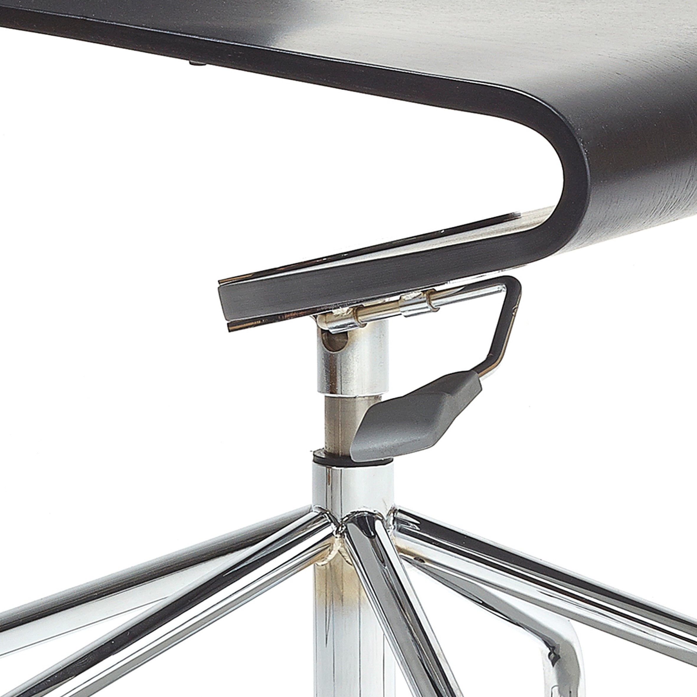 Close-up of the Seesaw Task Chair by Richard Lampert, featuring a sleek, curved black seat. The chrome metal legs form a triangular support that reflects light. A lever for height adjustment and rocking motion is visible beneath the seat, enhancing its minimalist and contemporary design.