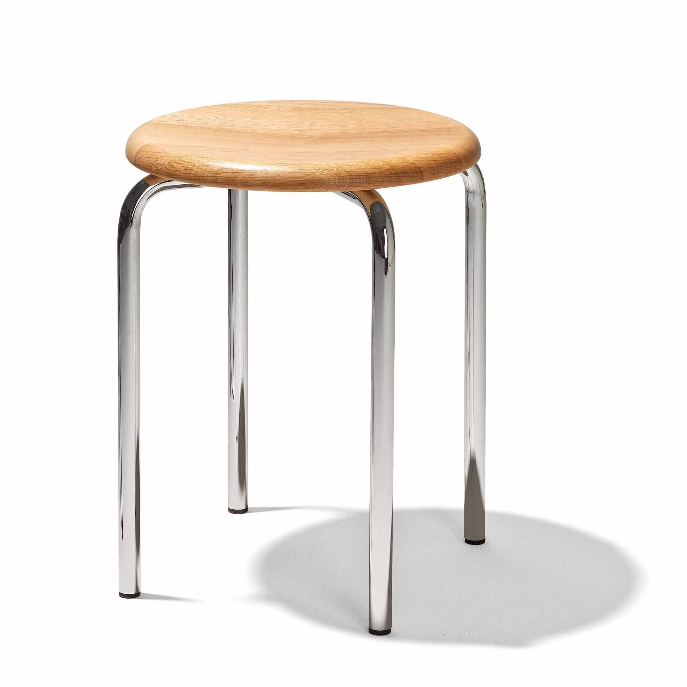 The Tom Stackable Stool by Richard Lampert features a round, smooth, light wood seat and three chrome legs, casting a soft shadow on a white background.