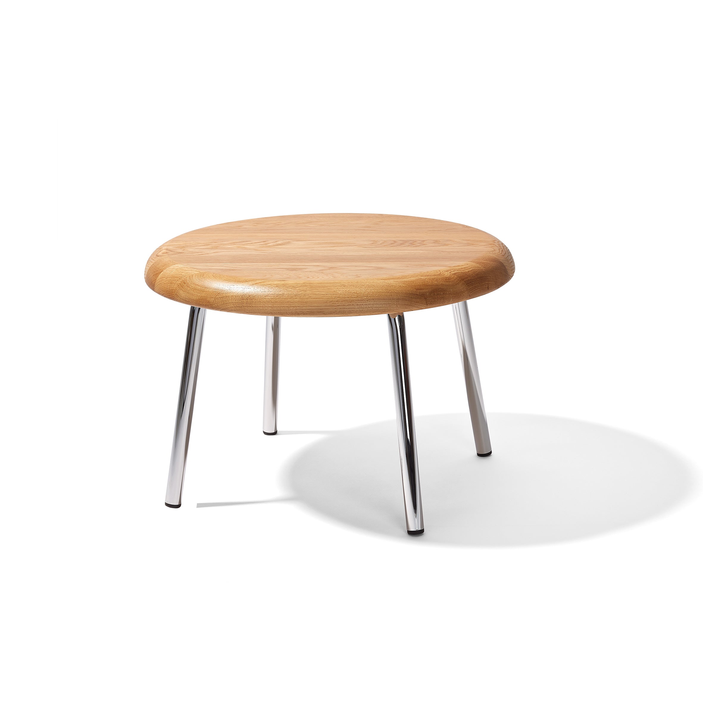 The Tom Side Table by Richard Lampert, featuring a small round solid oak top and four chrome-plated legs, is placed on a white background with visible shadows under the legs.