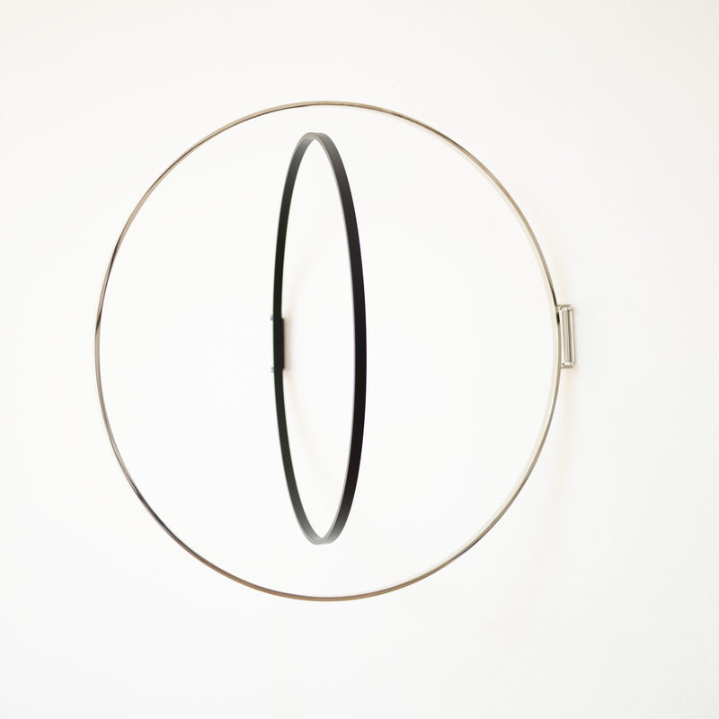 Atelier Haussmanns Rings is a minimalist metal hoop art piece with a large silver ring and smaller black ring, suspended parallelly, creating depth and balance against a plain white background.