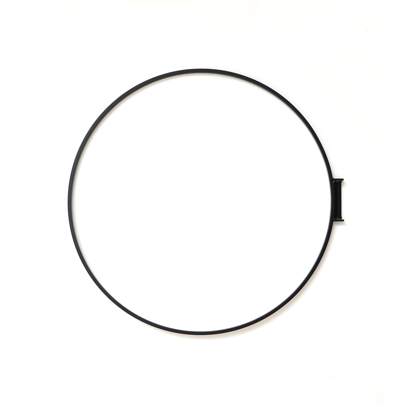 The Rings decorative object by Atelier Haussmann is a thin black metal hoop that mounts on a white wall, forming a large circle with a small rectangular attachment.