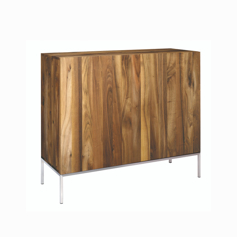 The SB03 FARIBA by E15 is a wooden cabinet with a natural finish and vertical wood grain pattern. Its sleek design stands on slim metal legs with stainless steel touches, offering a modern look while keeping minimalist elegance.