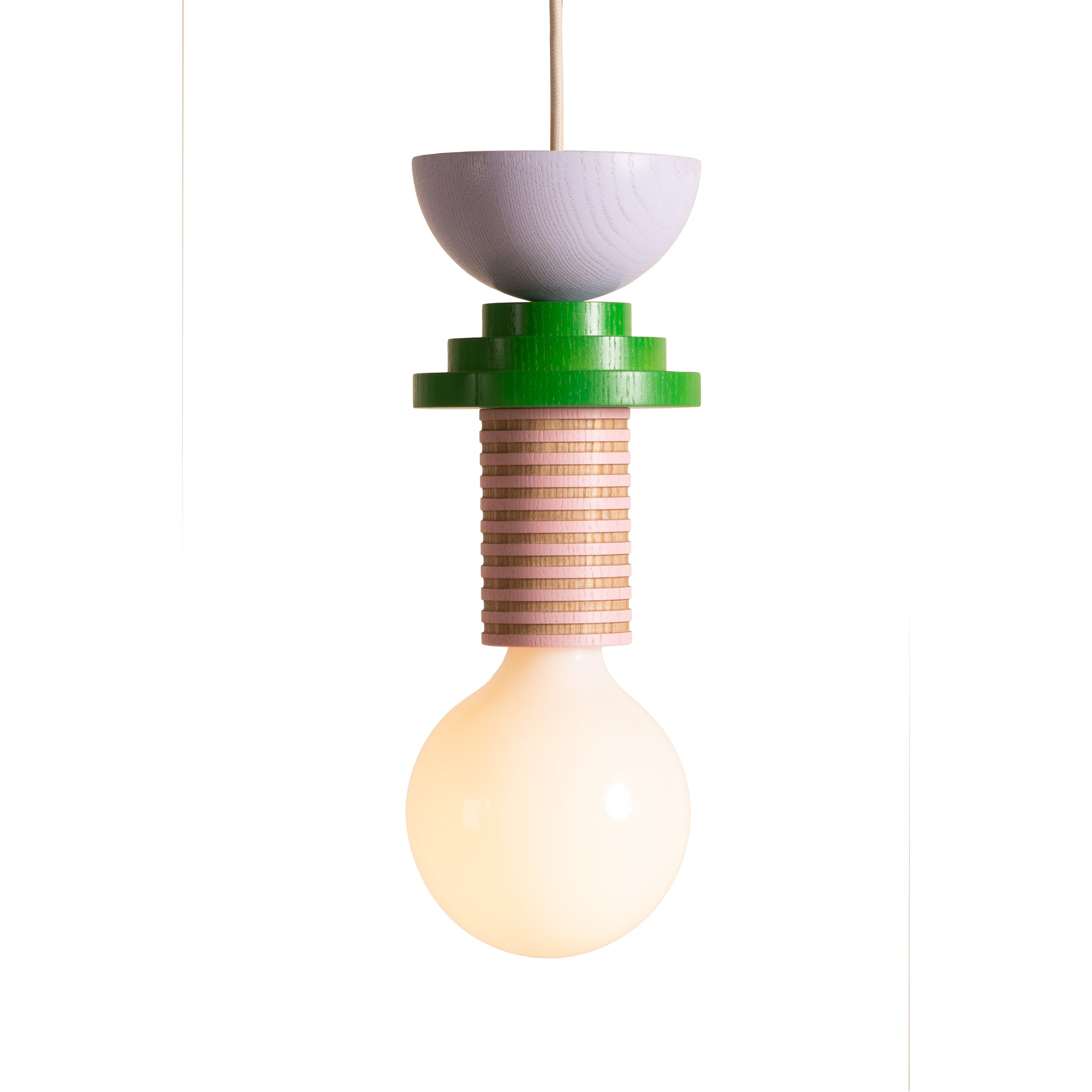 The Schneid Junit Gelato pendant light, with its modern design and round bulb, hangs vertically to provide ambient lighting. It showcases a Bauhaus-inspired aesthetic with a green and natural wood-color layered look, finished with a small light gray dome on top.