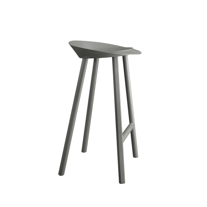 The ST10 JEAN bar stool by E15 showcases a minimalist design with a sleek, curved seat made from oak-veneered plywood. It features four slender legs, a muted gray finish, and includes a footrest for enhanced comfort and functionality.
