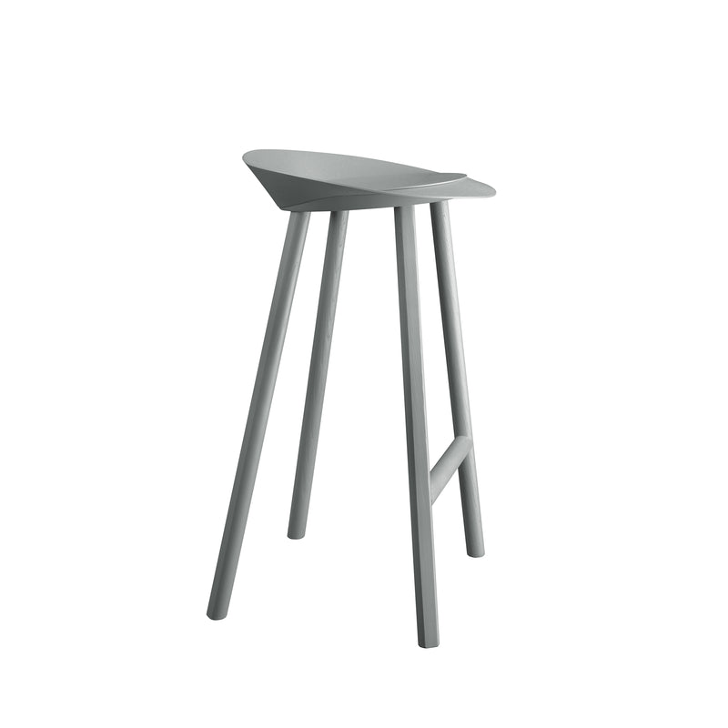 The ST10 JEAN by E15 is a modern, minimalist bar stool with oak veneered plywood, featuring a smooth curved seat and four angled legs in a uniform light gray color. It stands elegantly against a plain white background, highlighting its sleek design.