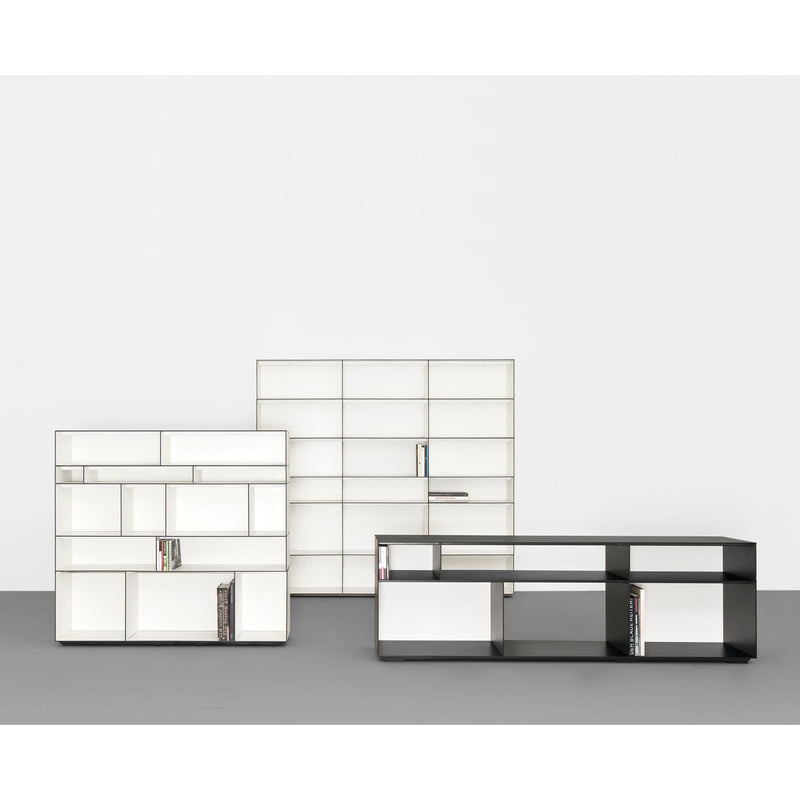 Against a plain wall, the modern Digital multipurpose shelf system by Sanktjohanser features open compartments with two white and one sleek HPL black shelf. A few books provide contrast to the minimalist designs elegant simplicity.