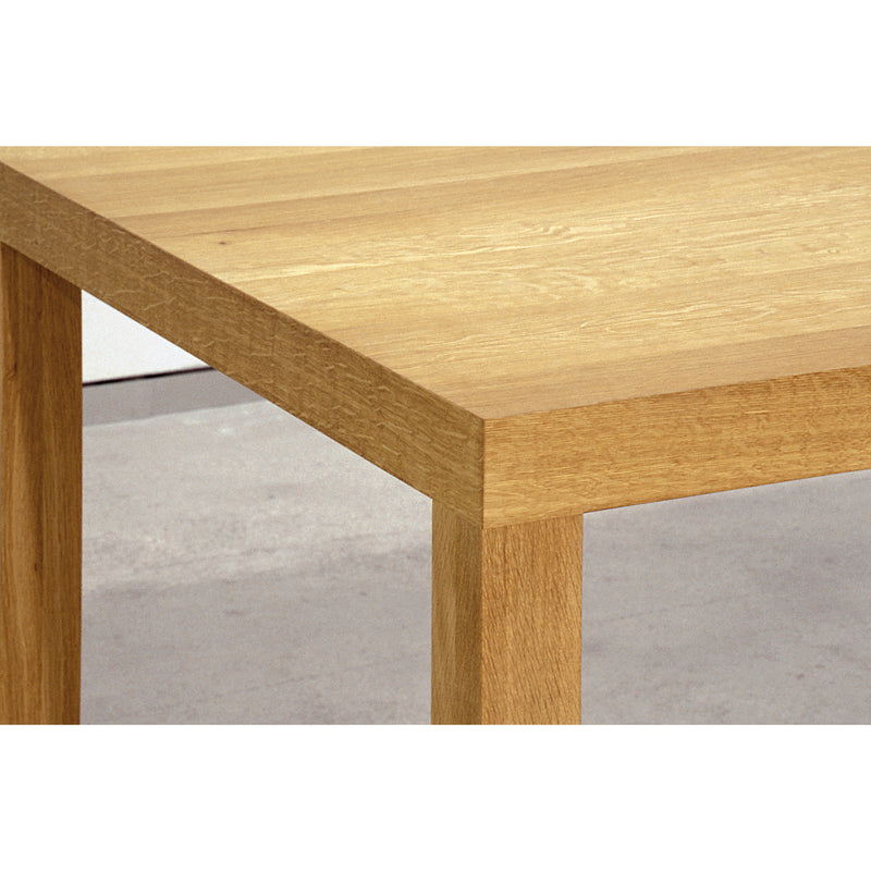 A close-up of the Sanktjohanser Dinavier Table highlights the grain texture of its solid wood tabletop and legs. The light-colored wood with a natural finish contrasts elegantly against a neutral background.