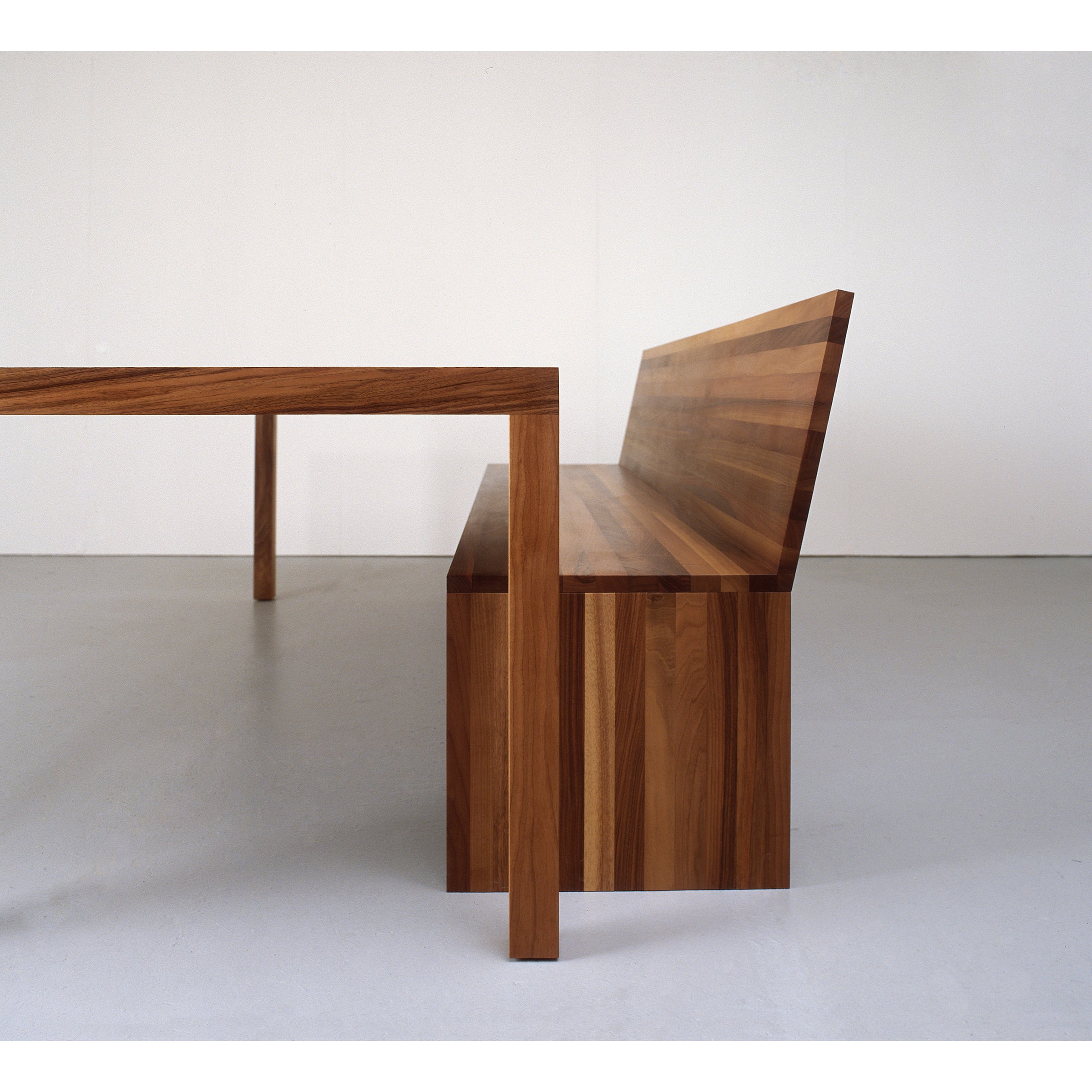 The Sanktjohanser Dinavier Table and bench feature a sleek, minimalist solid wood design on a white background. The detachable legs allow the benchs backrest to align seamlessly with the table surface, emphasizing clean lines and natural wood grain.