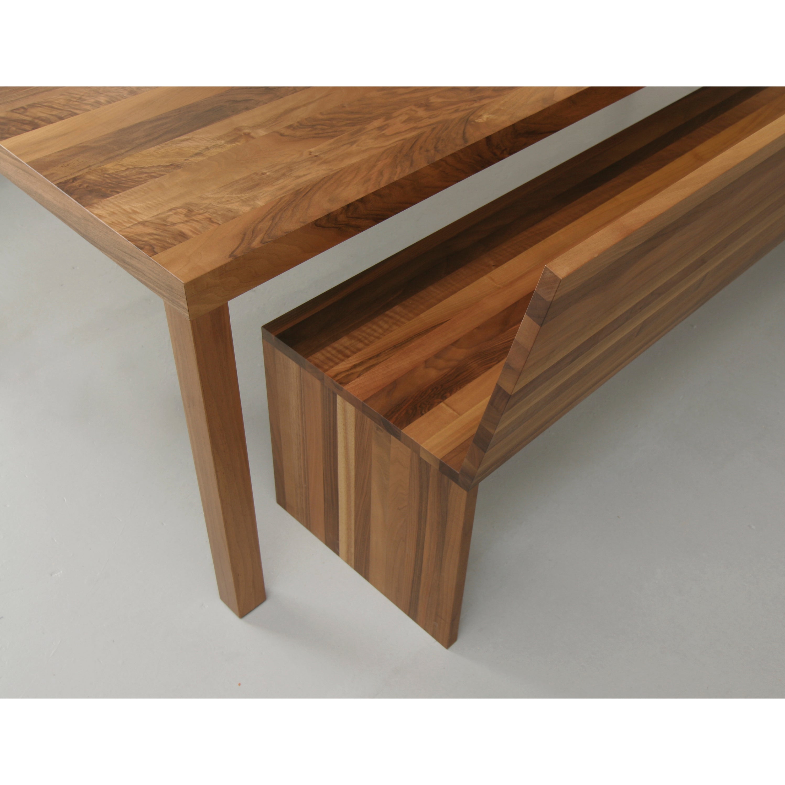 The Sanktjohanser Dinavier Table, made of striped solid wood, has a matching bench that fits perfectly underneath. Its minimalist design is accentuated by detachable legs on light gray flooring.