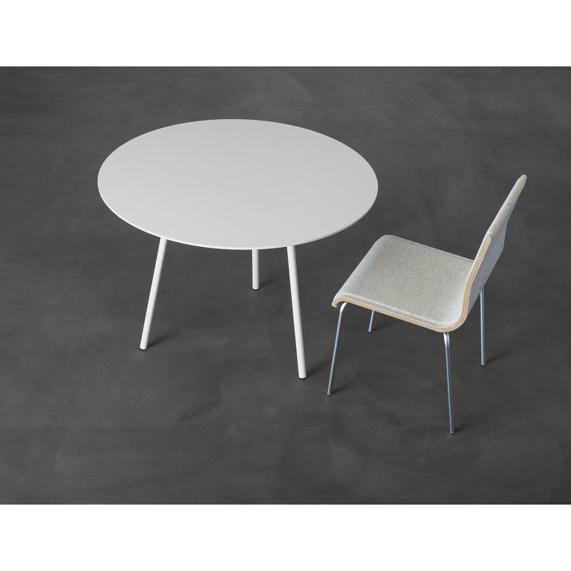 The Kontext Table by Sanktjohanser is a minimalist gray, round three-legged table made of round-bar steel. Its paired with a simple gray chair with a wooden backrest and metal legs. Custom sizes are offered to fit your space, all beautifully set on a dark gray floor.