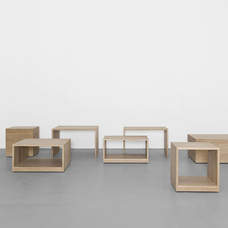 Sanktjohansers Relikt multipurpose tables and open cubes form a clean, modern geometric display on a smooth gray floor against a plain white wall, evoking minimalist modular furniture.