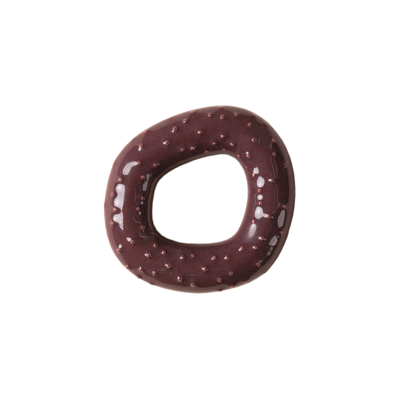 A Fossil Hooks donut by Schneid, featuring a glossy dark chocolate icing and an organic shape, viewed from above on a plain white background.