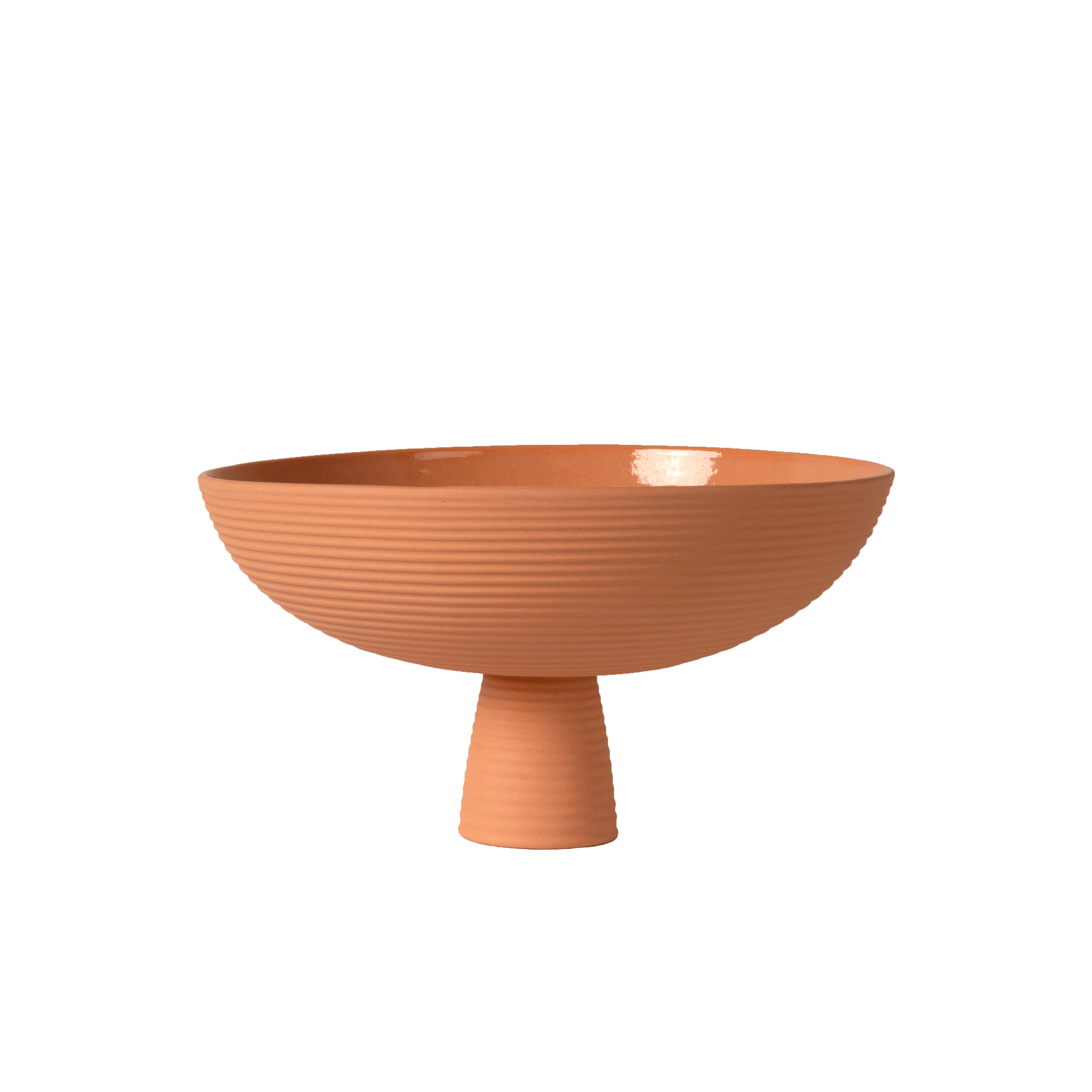 The Schneid Dais bowl, in terracotta with a textured surface, features a wide, shallow design and a short cylindrical pedestal. It elegantly contrasts against a white background, making it an ideal piece for modern homes.