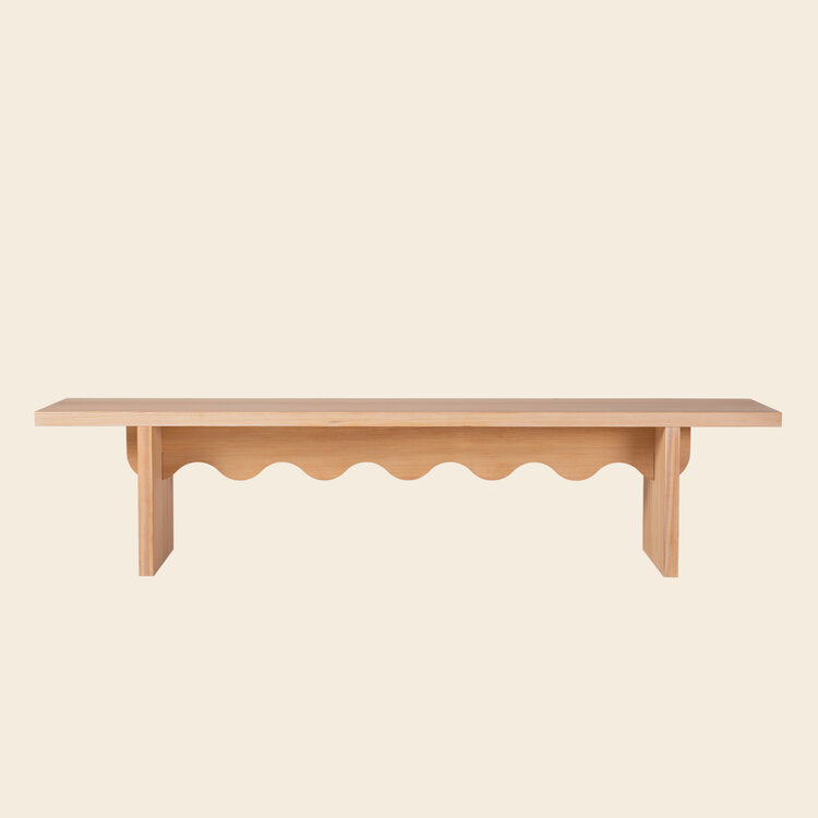 The Tami Bench by Schneid is a minimalist piece from the Tami Dining Collection, featuring a flat top and decorative wavy design under the seat, expertly crafted from larch wood.