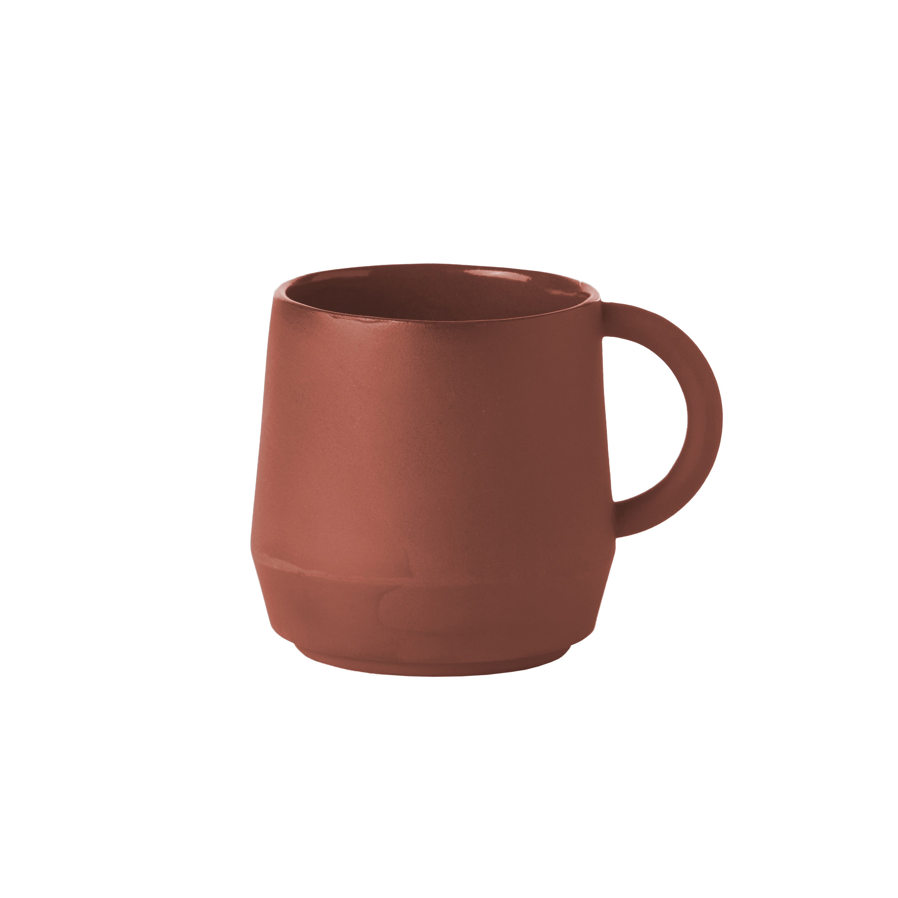 The Unison Cup by Schneid is a matte brown ceramic mug made with hand-mixed pigments, featuring a rounded body and sturdy handle. Its elegant design stands out against a white background.