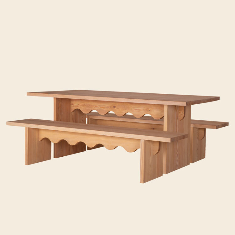 The Tami Dining Collection from Schneid includes a wooden dining set with a rectangular table and two benches by Julia Jessen, featuring a unique wavy design. Its crafted from naturally oiled larch wood with a smooth finish against a plain beige background.