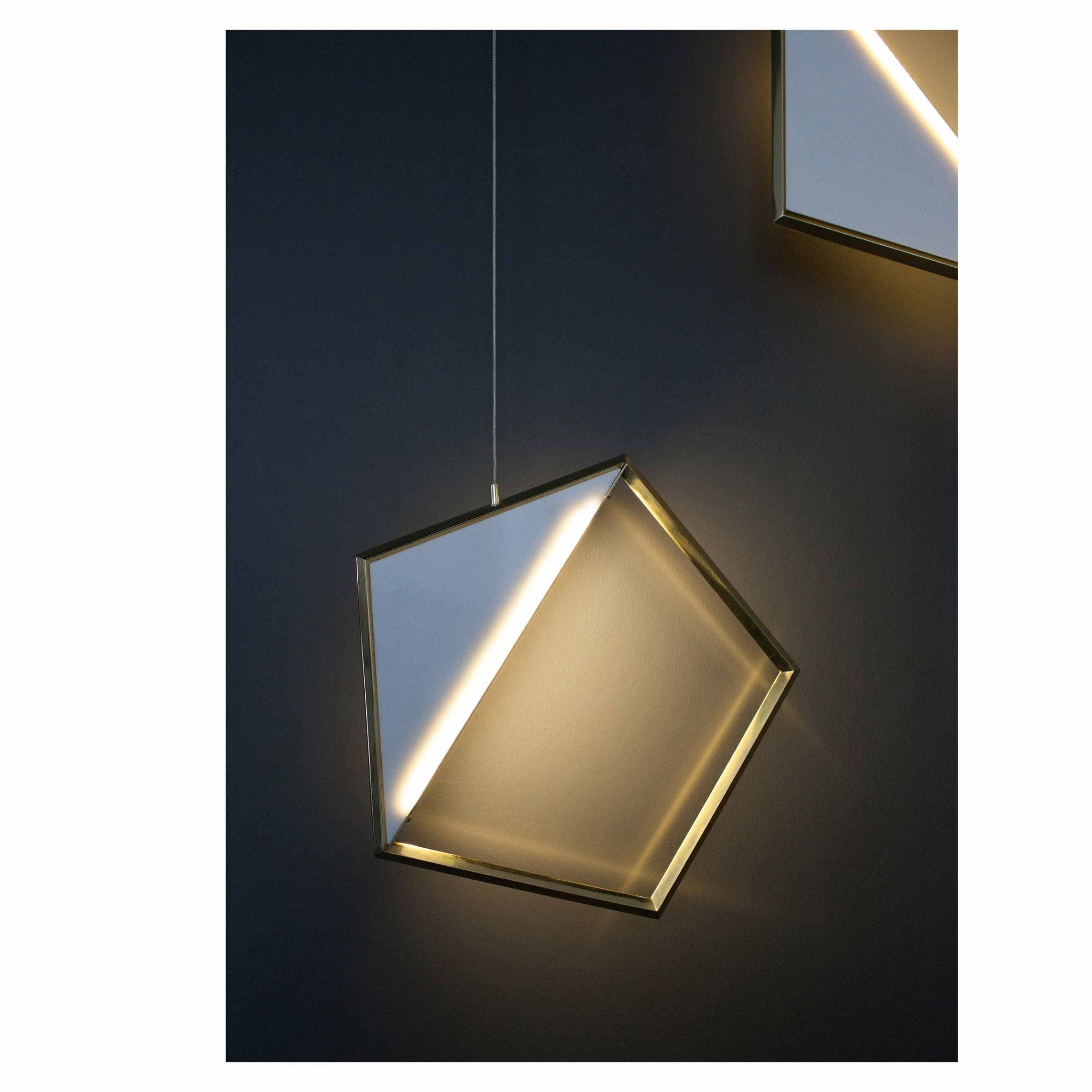 The Tangle Light by Coordination Berlin is a sculptural pendant with a modern, geometric design. Against a dark background, its tilted pentagon shape and glowing edge emit soft ambient light, echoing jewelrys elegance.
