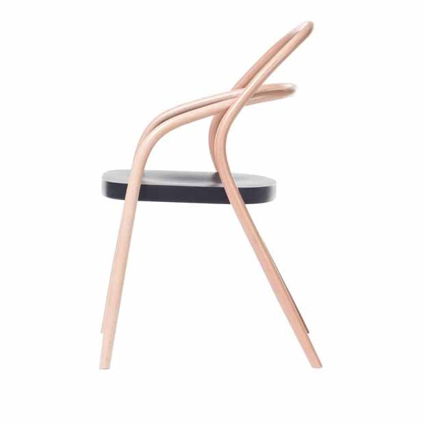 A side view of Chair 002 by TON reveals a minimalist design with a sleek, curved wooden frame and a black seat, reminiscent of a classic model redesign.