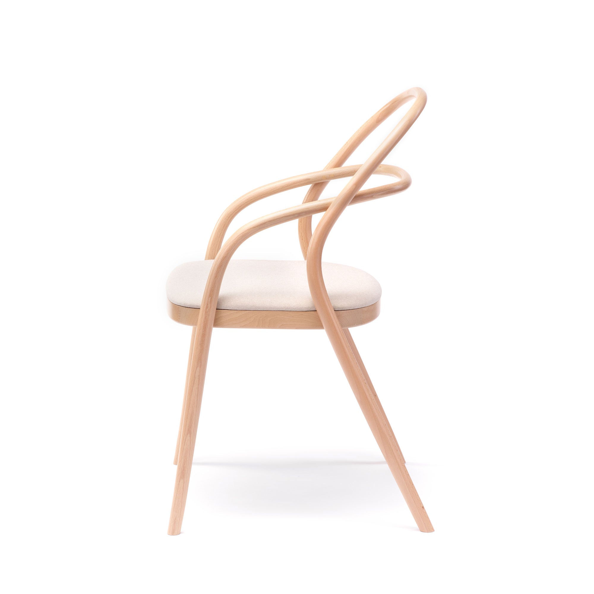A side view of the sleek Chair 002 - Upholstered by TON, featuring a minimalist No. 14 redesign with a uniquely curved backrest and cushioned light fabric seat, all in elegant light wood tones.